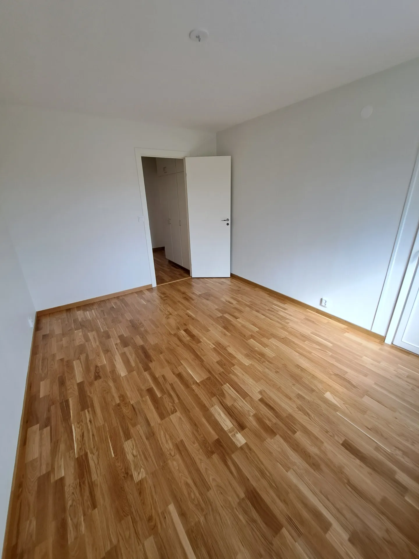 Ljust sovrum med ekparkett och nymålade väggar